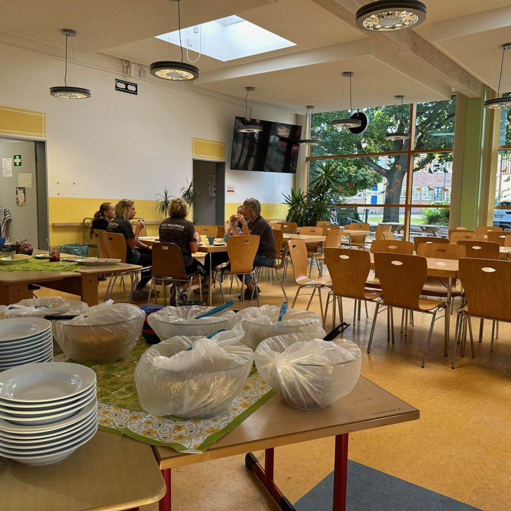 Speisesaal mit gedecktem Buffet und vier Personen an einem Tisch im Hintergrund