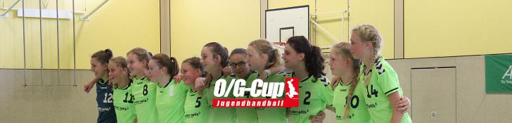 Jugendhandballteam in grünen Trikots steht zusammen in einer Sporthalle mit Armen umeinander